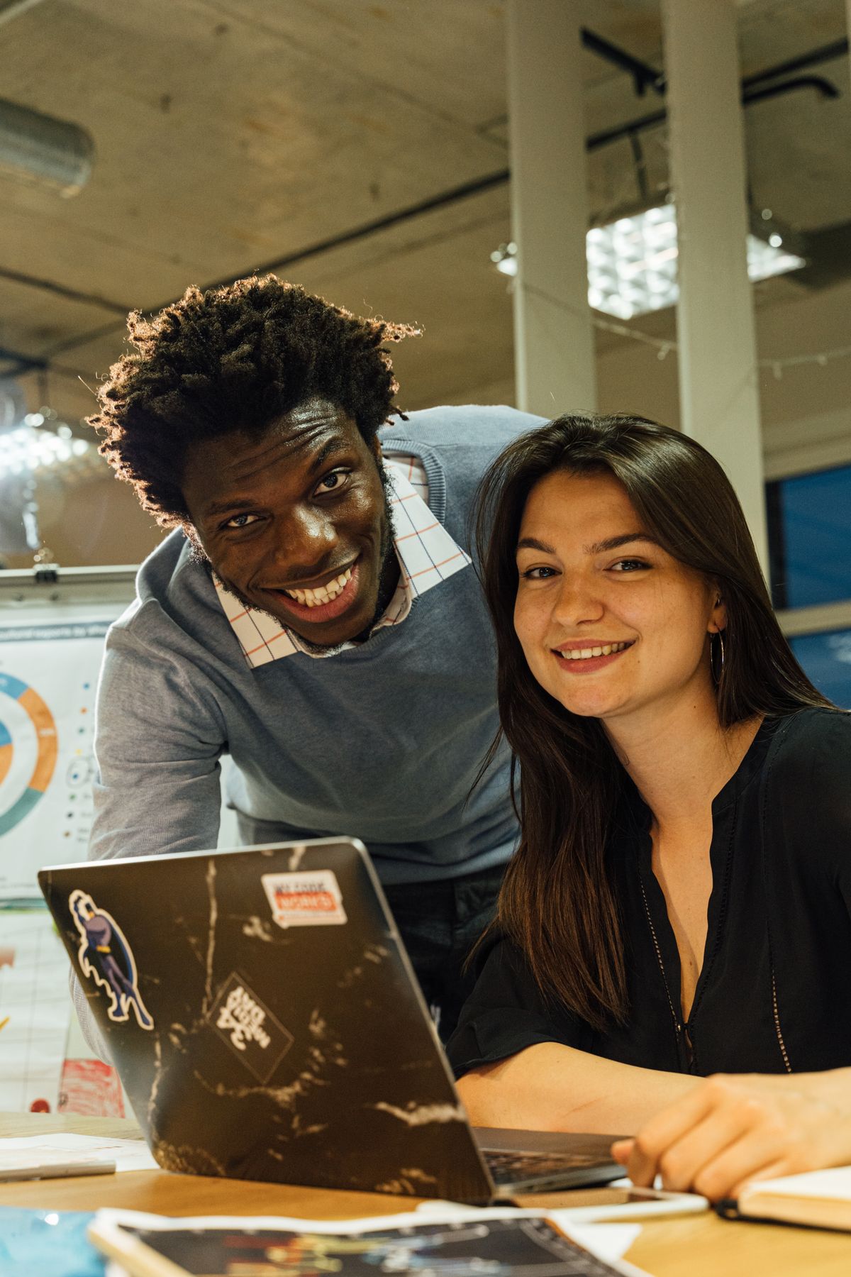 Two early career Salesforce coworkers collaborating at a laptop in a modern office