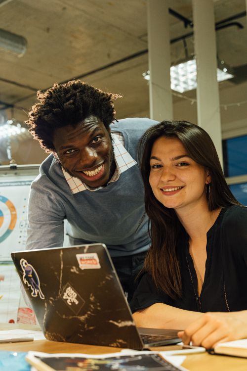 Free Two diverse coworkers smiling while working together in a modern office. Stock Photo
