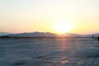 机场跑道上，太阳从远处的山间升起，投下柔和的光芒