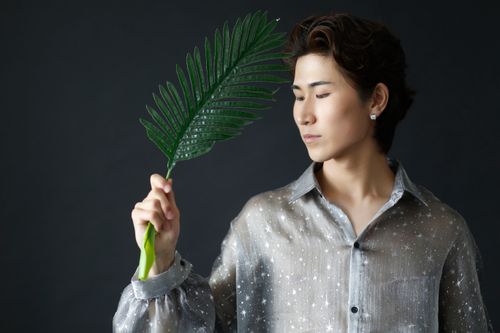 Free Stylish man posing with a green leaf in a studio portrait. Stock Photo