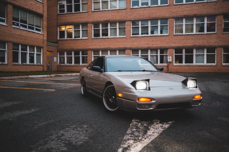 Old Car With Bright Headlights Near Shabby Building