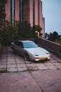 Stylish automobile parked near fence of contemporary house with green bushes and trees