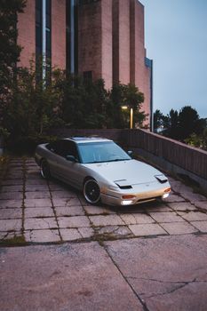 Stylish automobile parked near fence of contemporary house with green bushes and trees