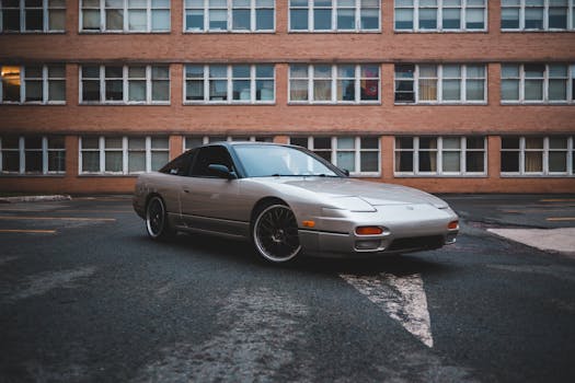 Trendy silver automobile parked on asphalt surface with peeling paint near brick building