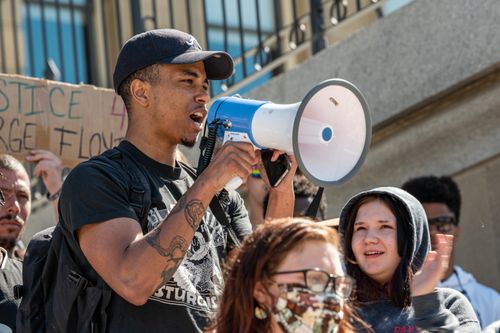 Free Low angle of African American male talking on megaphone near diverse protesters on street in daylight Stock Photo