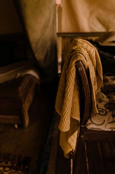 Soft creased towel with ornament hanging on chair in aged building on blurred background