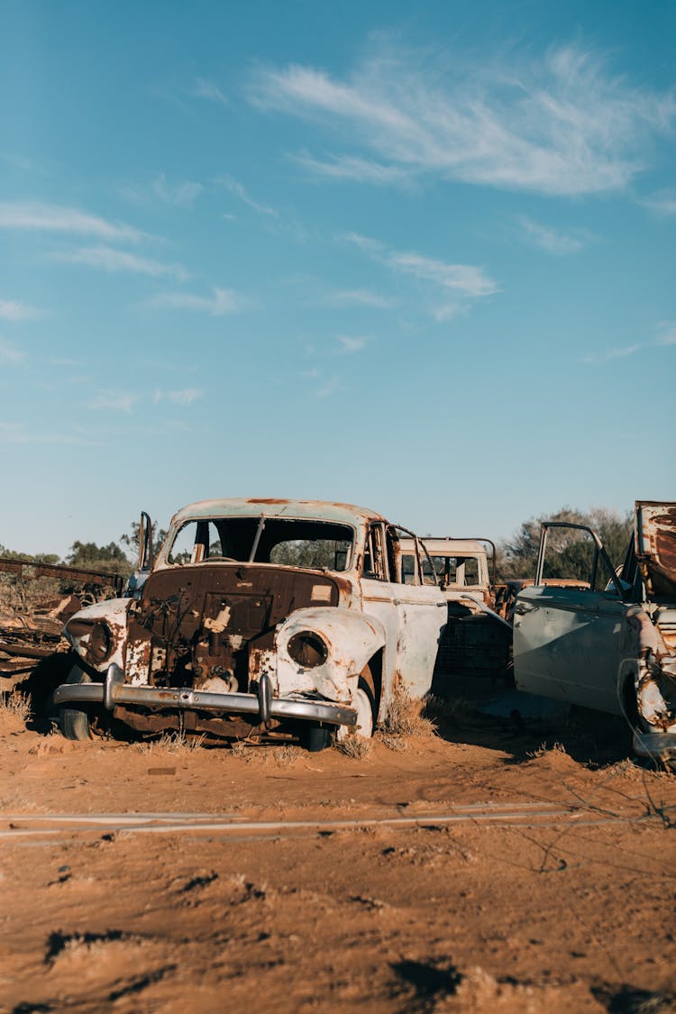 Old Rusty Cars In Desert Under Cloudy Sky