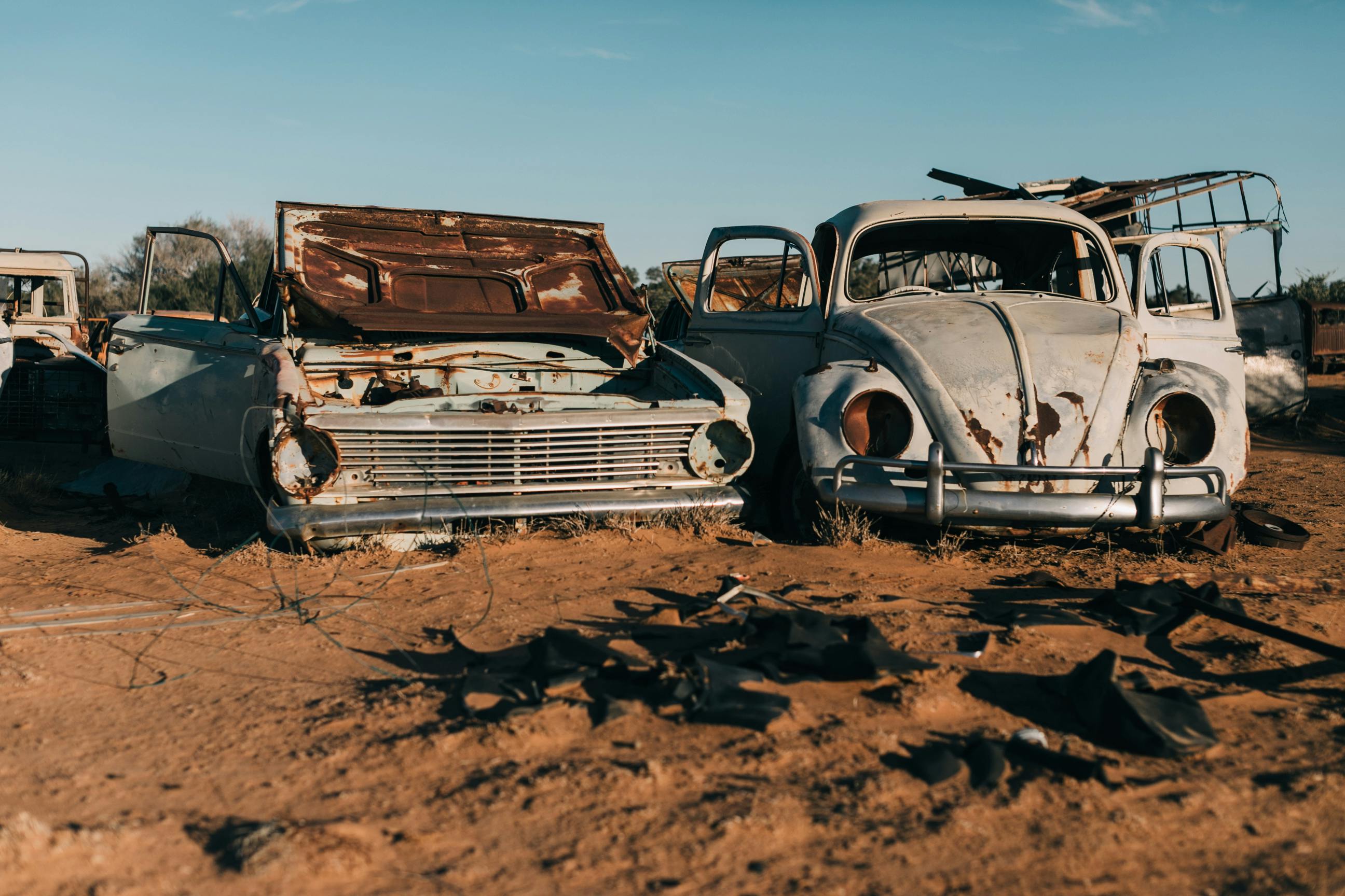 damaged retro cars in desert under blue sky