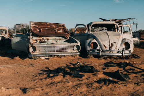 Damaged retro cars in desert under blue sky