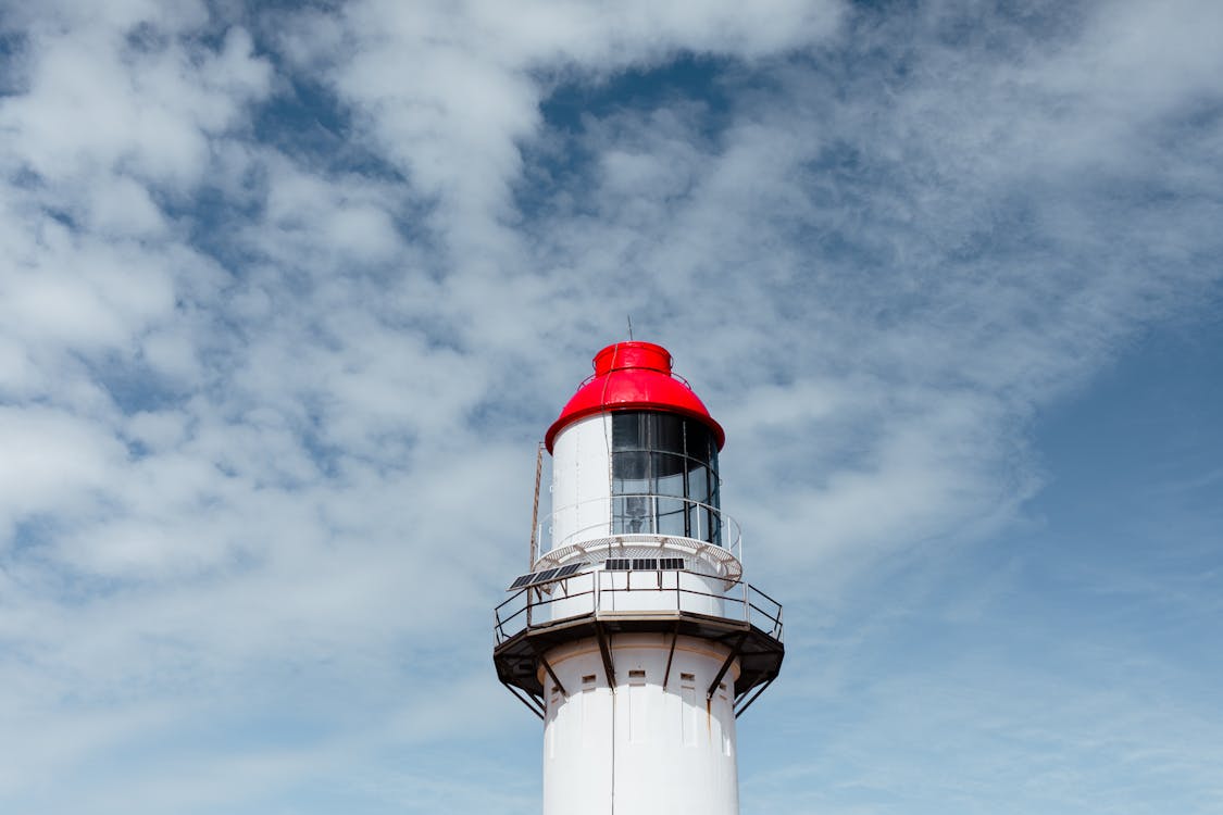 Bright aged lighthouse under cloudy sky in daytime