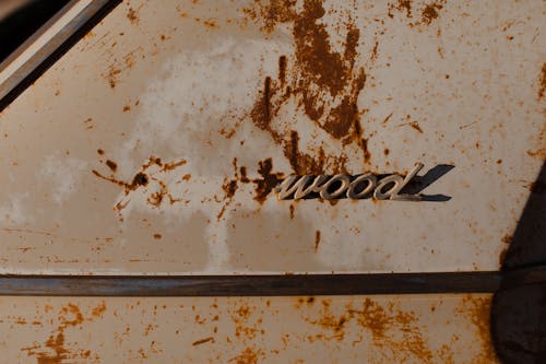 Corroded stains on part of old automobile with fragment of brand name written by metal letters