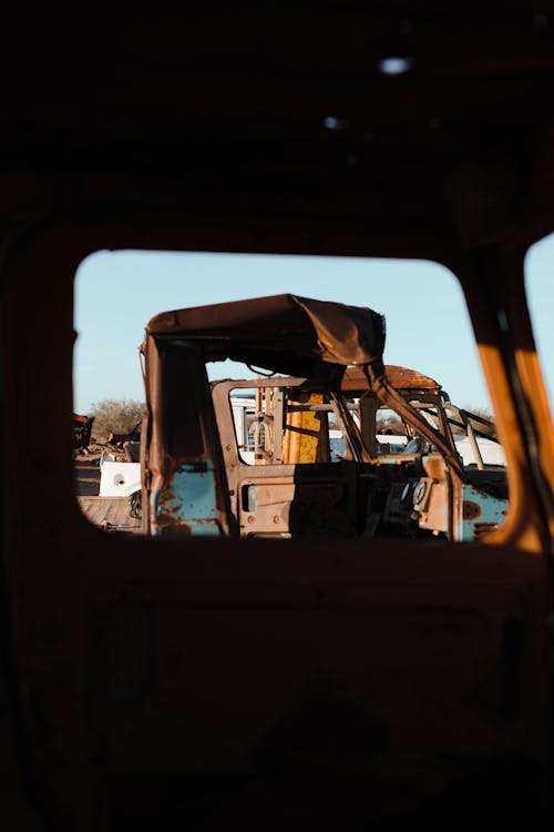 View from old auto on abandoned rusty damaged cars in sandy area in daytime standing in row