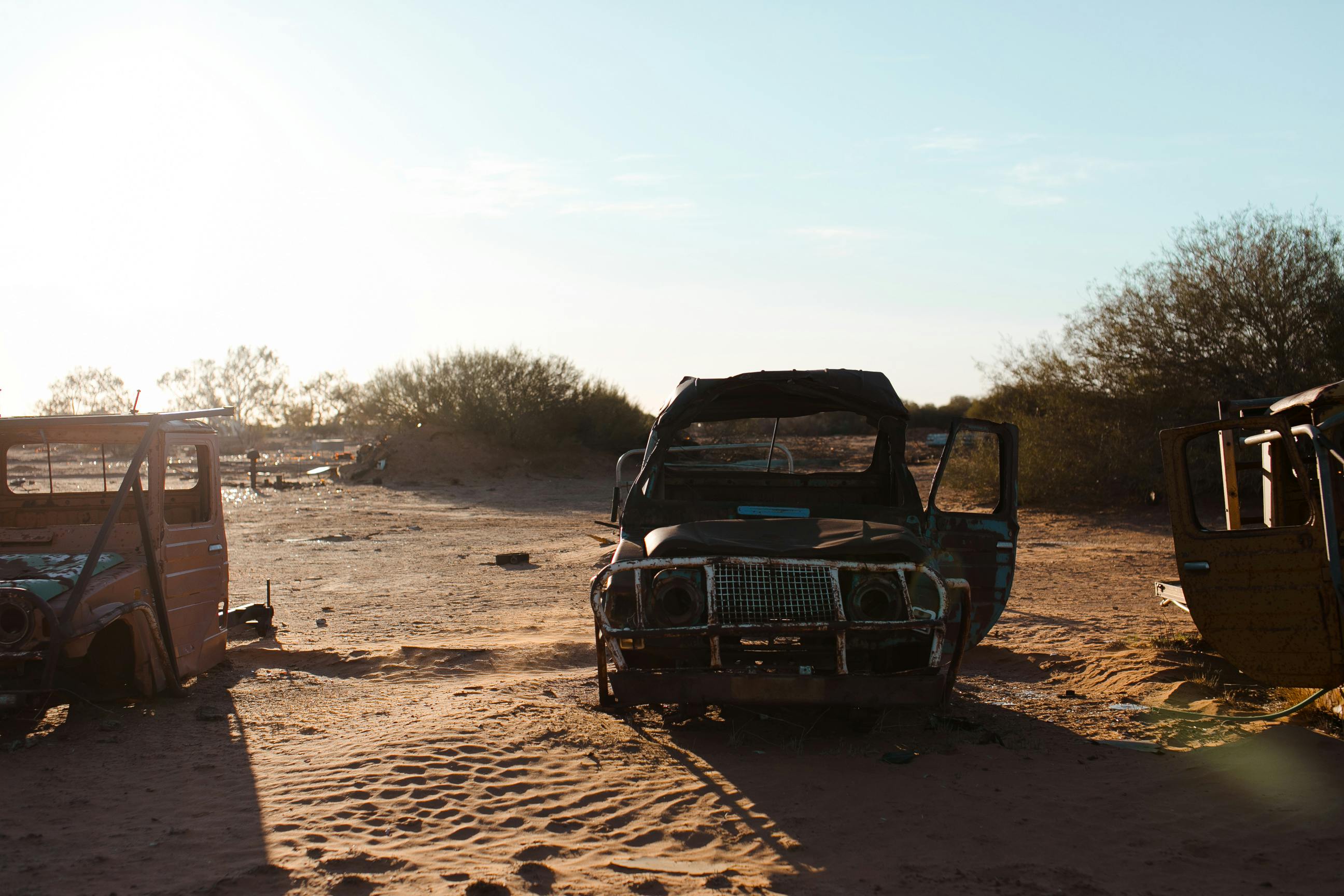 rusty broken cars placed on sand