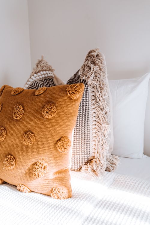 Free Comfortable colorful pillows placed on soft bed in light apartment illuminated by sunlight Stock Photo