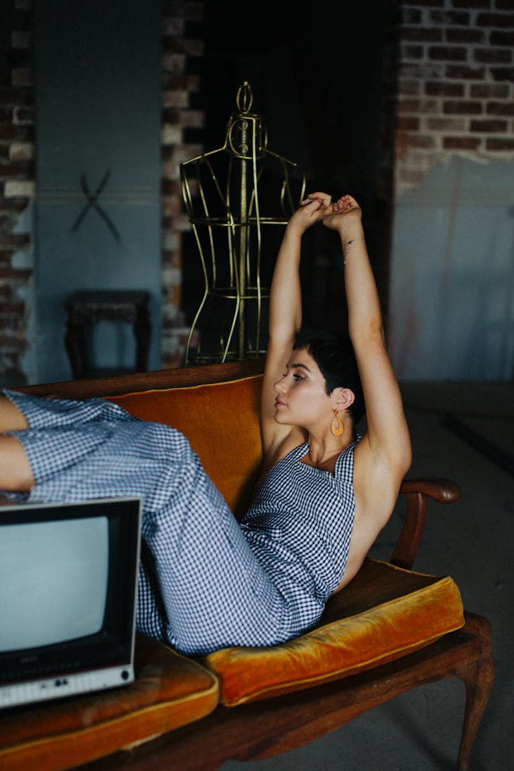 Woman Sitting On Settee With Old Fashioned TV Set