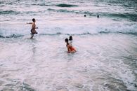 High angle of travelers running and swimming in foamy waves of sea in tropics