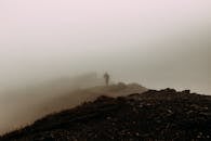 Silhouette of person standing on hilltop in haze