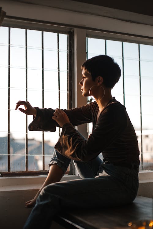 Free Tranquil woman sitting in solitude near window Stock Photo