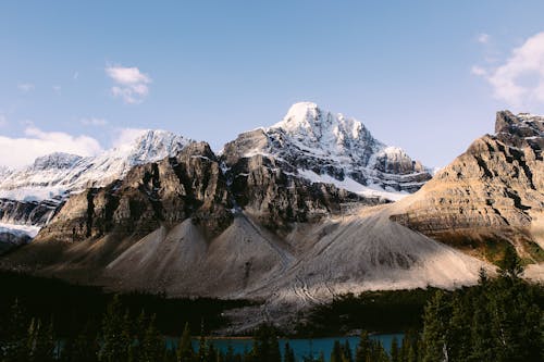 Snowy mountain peaks near river and evergreen forest