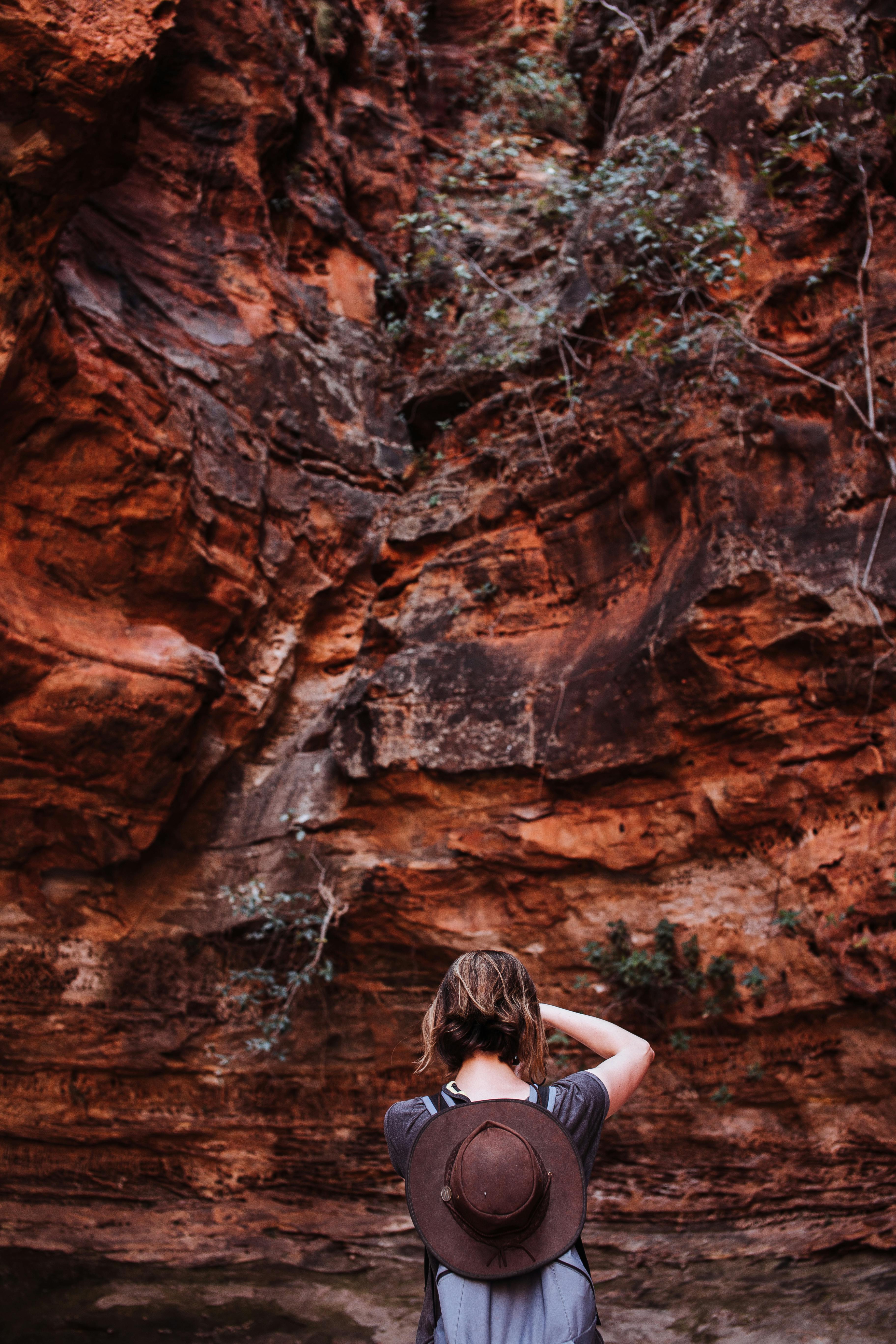 traveler with backpack standing near rocky slope