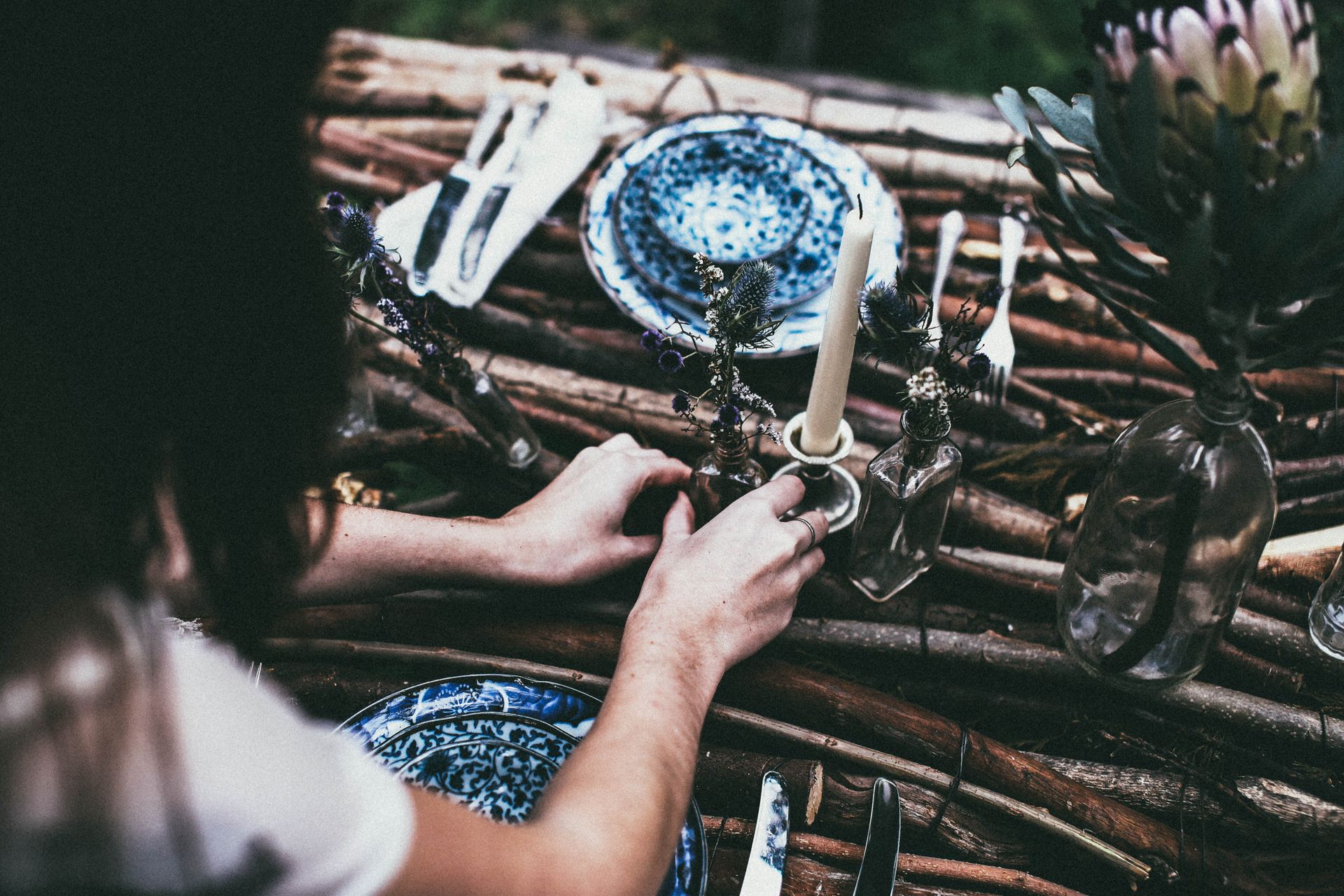Rustic boho table setting outdoors with floral decor and candlelight.