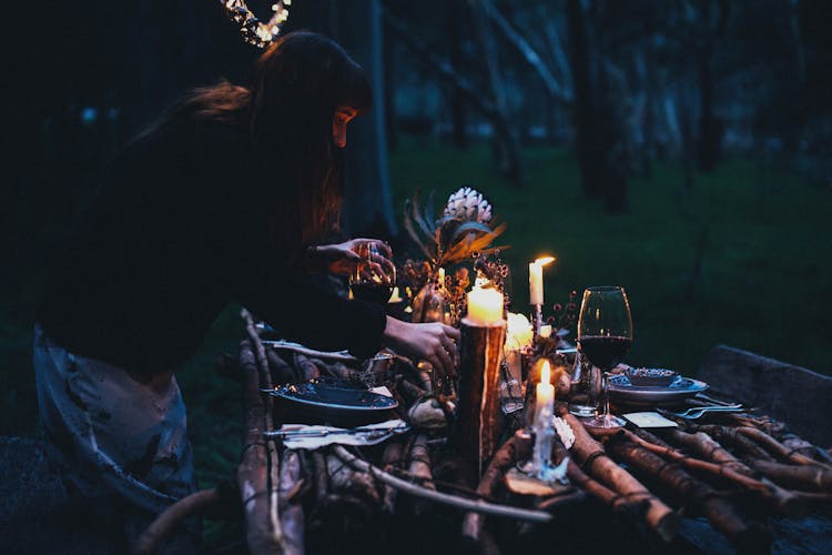 Anonymous Female Putting Tableware On Wooden Surface With Decorative Elements