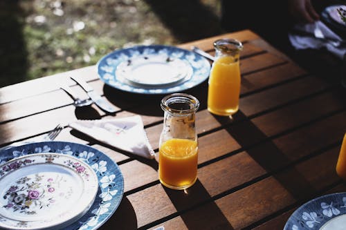 Table setting with plates and bottles with juice near cutlery