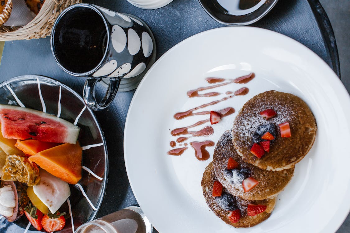 Delicious breakfast with pancakes and berries near fruits