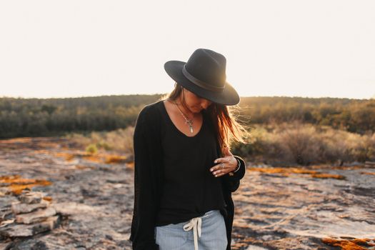 Anonymous woman in hat on stony terrain