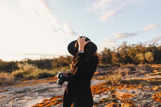 Unrecognizable woman in hat and photo camera in nature