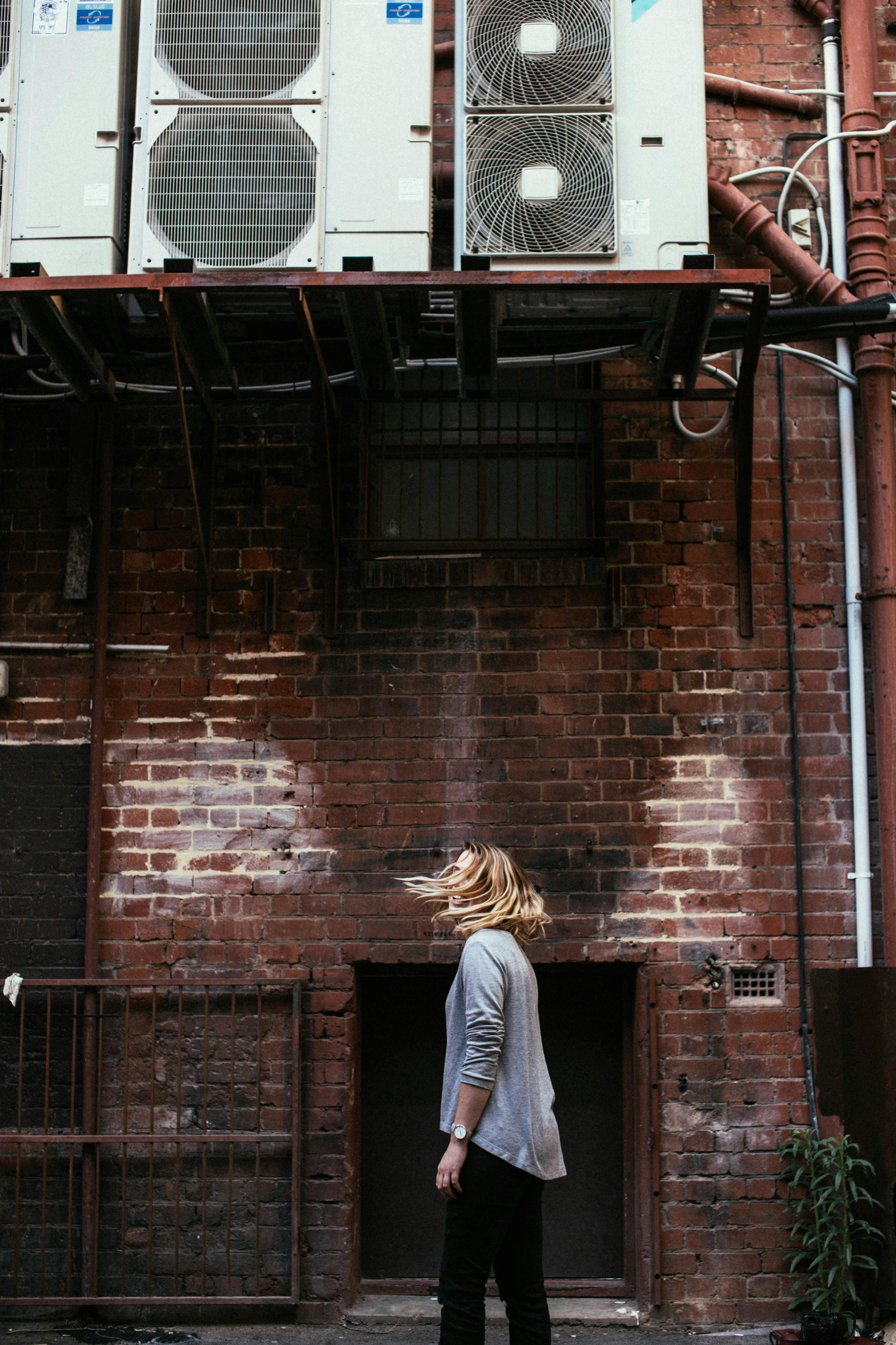 anonymous woman standing near brick building