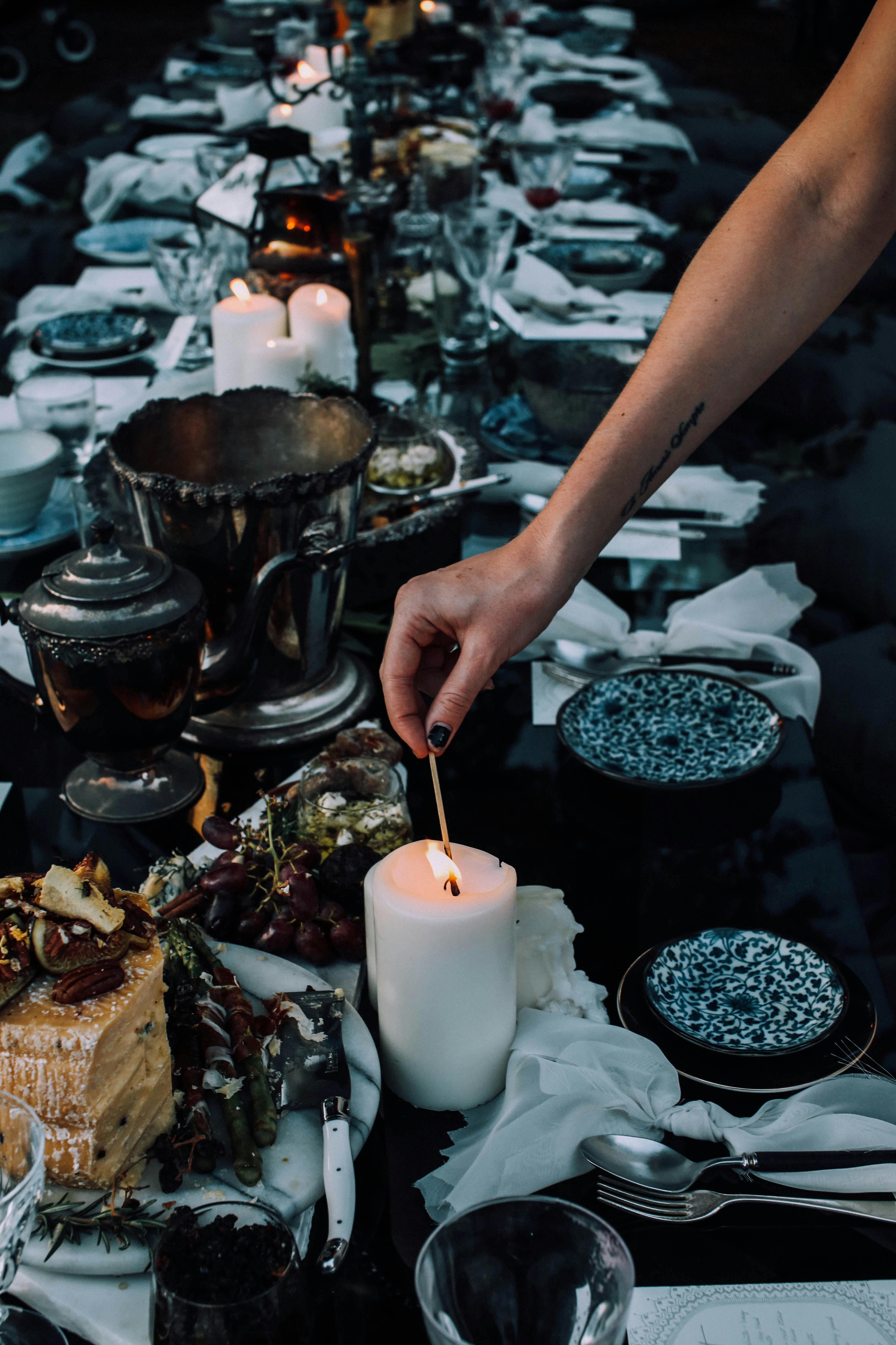 crop woman lighting candle while serving table