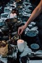 Crop woman lighting candle while serving table