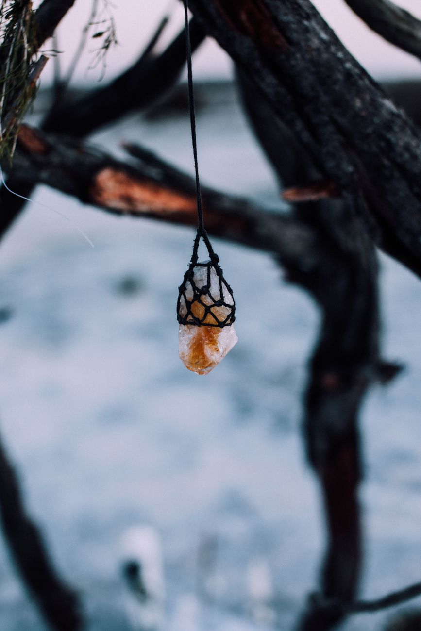 Mineral stone hanging in knitted sack on tree on blurred background of nature