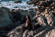 Lady sitting on rocky coast of sea