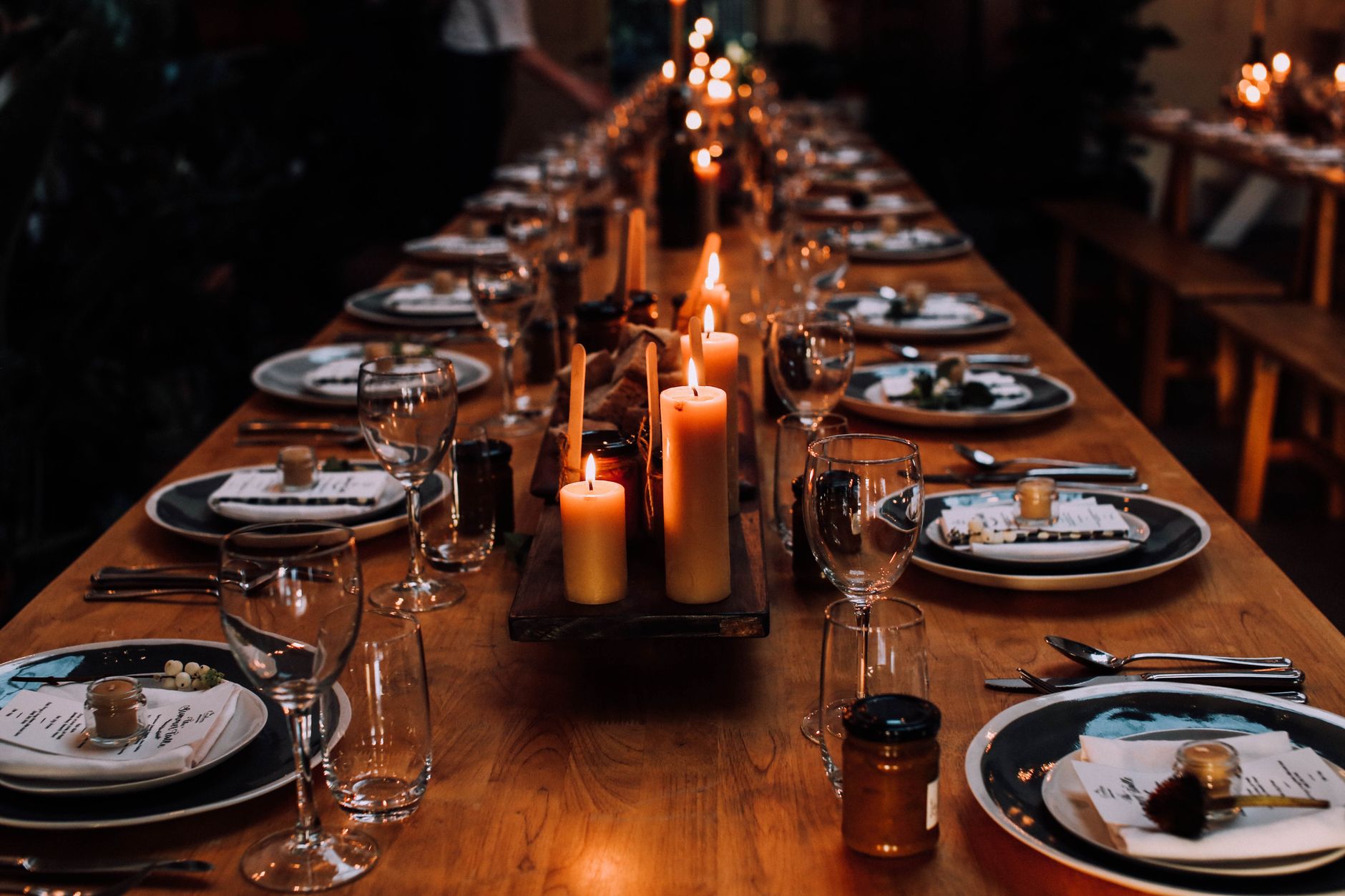 A long table set with candles in a dark, warm room