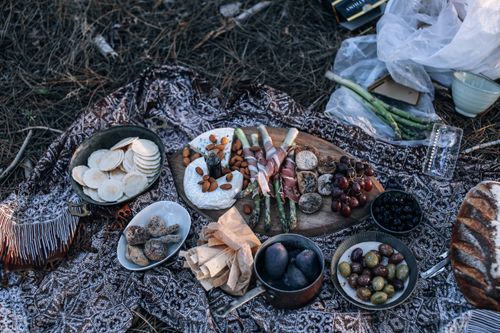 Free From above of appetizing homemade bread and cheese placed near fruits and vegetables in bowls and on wooden cutting board for picnic on nature Stock Photo