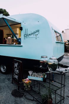 A retro blue food truck in a city street serving beverages with stylish outdoor decor.