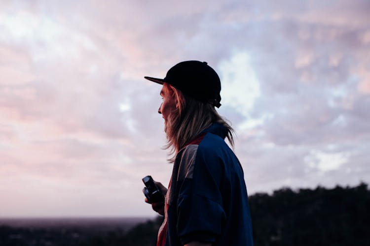 Young Traveler In Cap Under Cloudy Sky