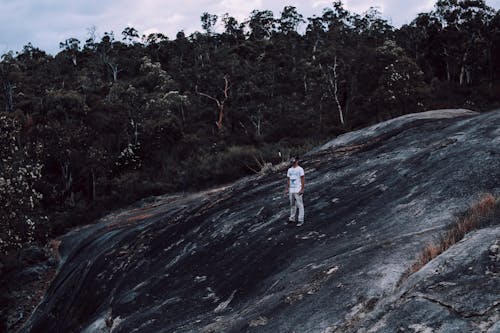 Mysterious man in mask on rocky formation in forest