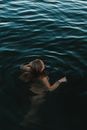 From above of anonymous female swimming in rippling calm water of clean pond in summer