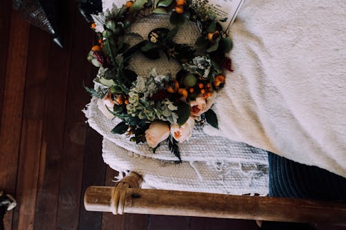 Top view of fresh wreath with delicate roses and verdant leaves placed on timber bed