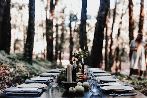 Free Elegant table setting with glassware and candles with green apples prepared for event on blurred background of nature Stock Photo