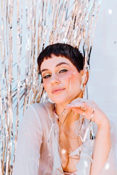 Portrait of an elegant woman with short dark hair surrounded by festive silver foil decorations.