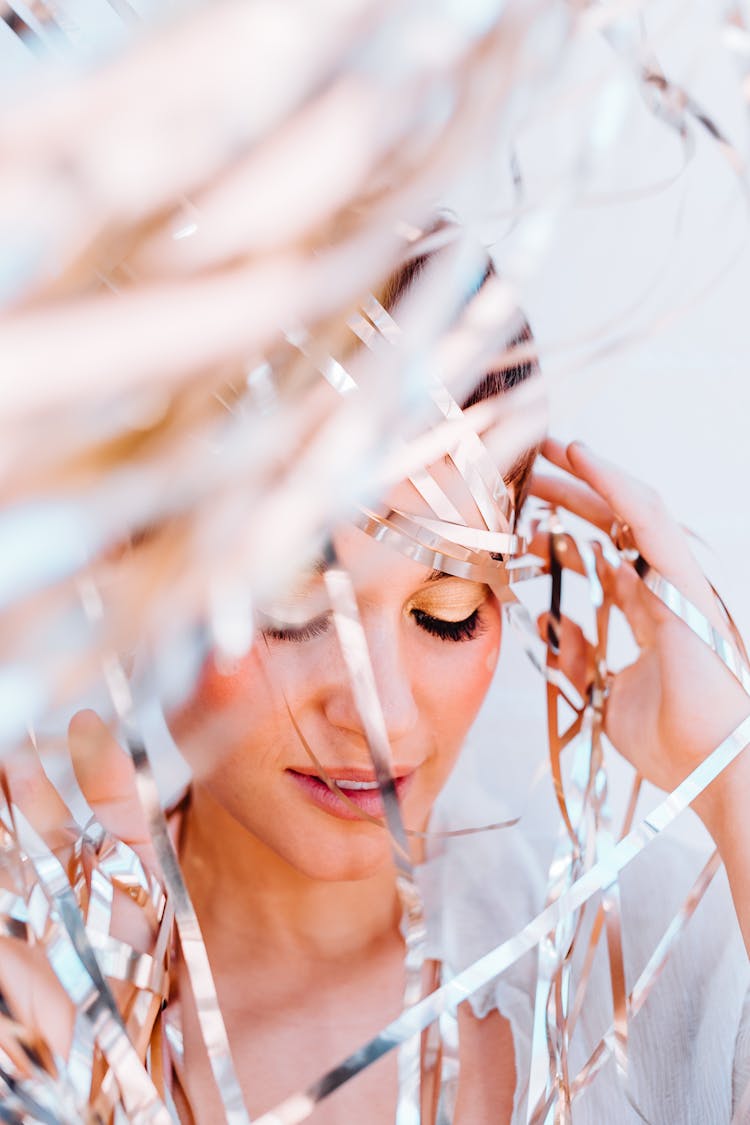 Dreamy Young Woman Amidst Decorative Foil Curtain