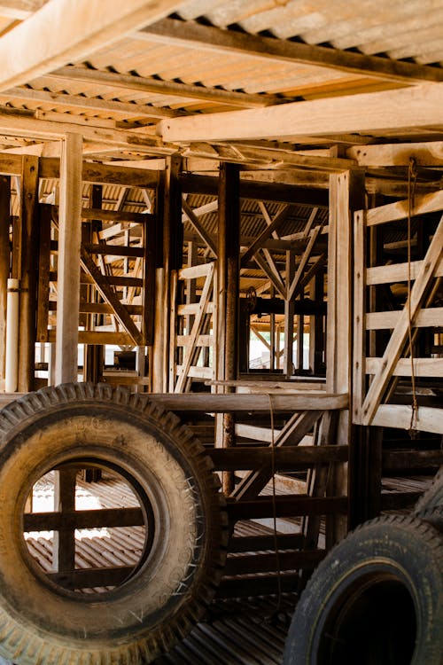 Various rubber tires stacked in aged wooden barn in countryside on sunny day