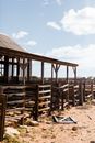 Destroyed wooden barn on sandy terrain in sunlight
