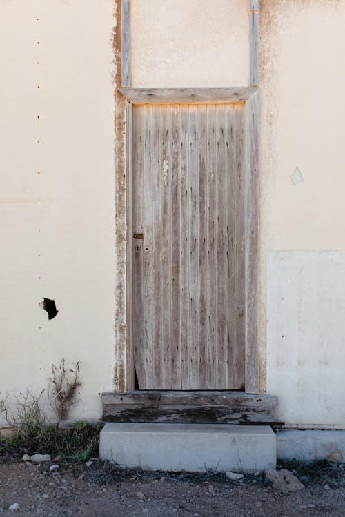 Old wooden door of shabby white house in countryside