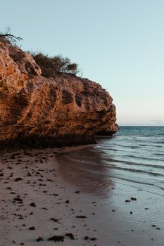 宁静的海滩、崎岖的悬崖、平静的水域以及日落时的自然美景，构成了一幅和谐的画面