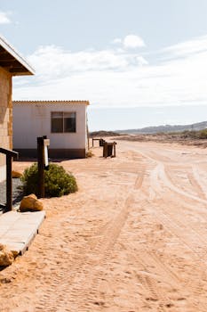 在郊区的沙质地面上，散落着轨道和带楼梯的小别墅碎片，天空多云